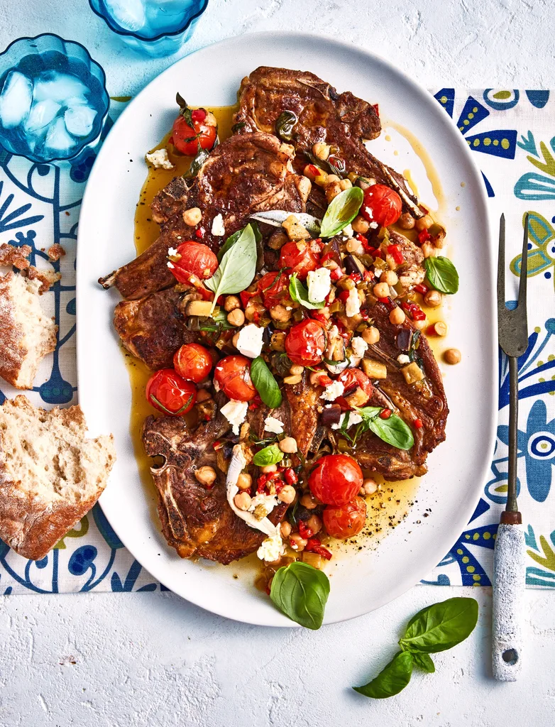 CONFIT TOMATOES WITH LAMB CHOPS ON A LARGE OVAL WHITE SERVING DISH