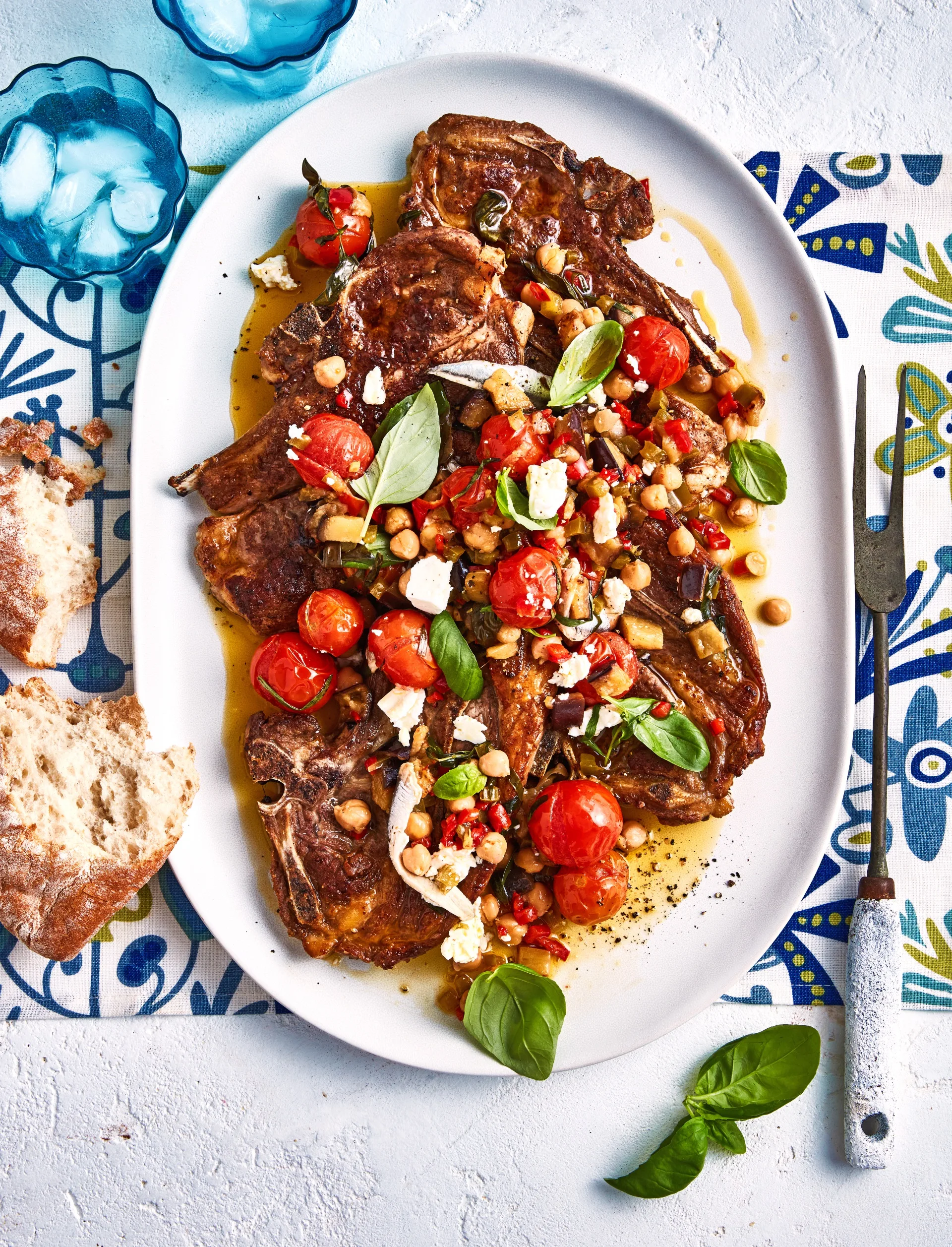 CONFIT TOMATOES WITH LAMB CHOPS ON A LARGE OVAL WHITE SERVING DISH