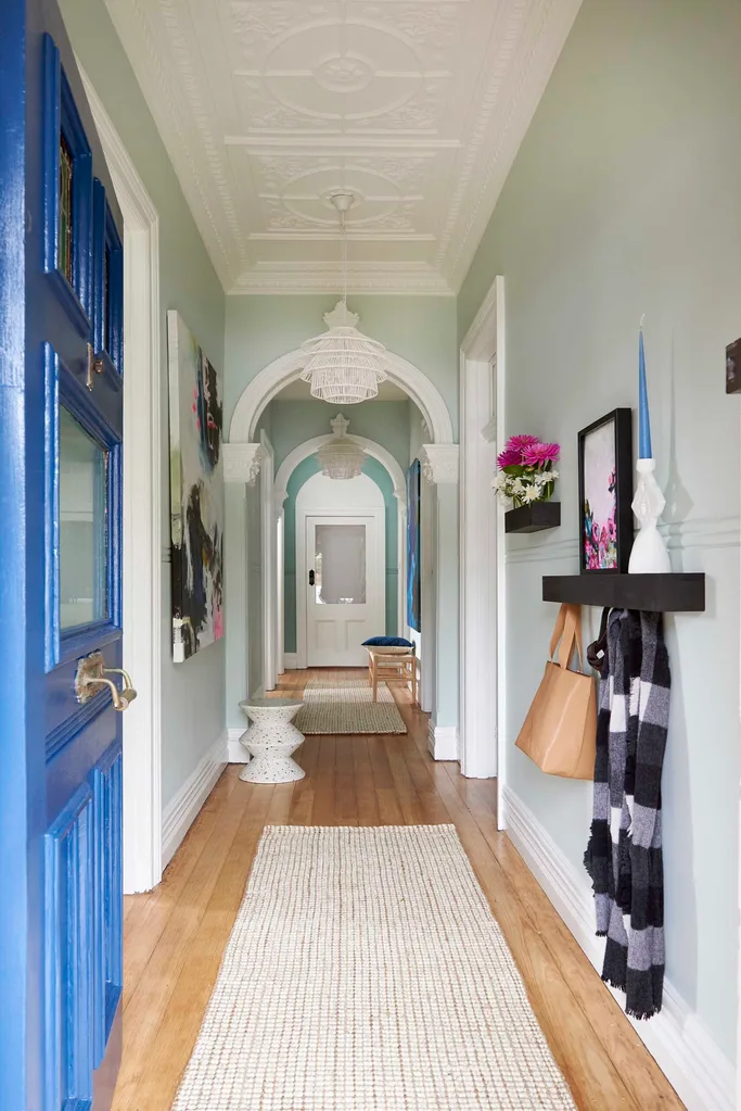 Blue front door opening into a long hallway of a home.