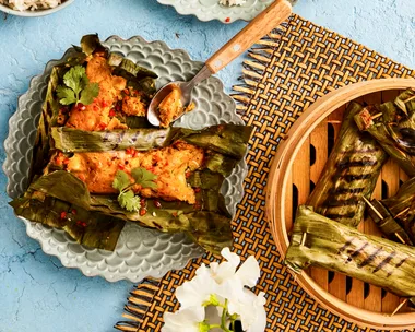 fish cakes wrapped in banana leaves on two separate plates with rice on the side