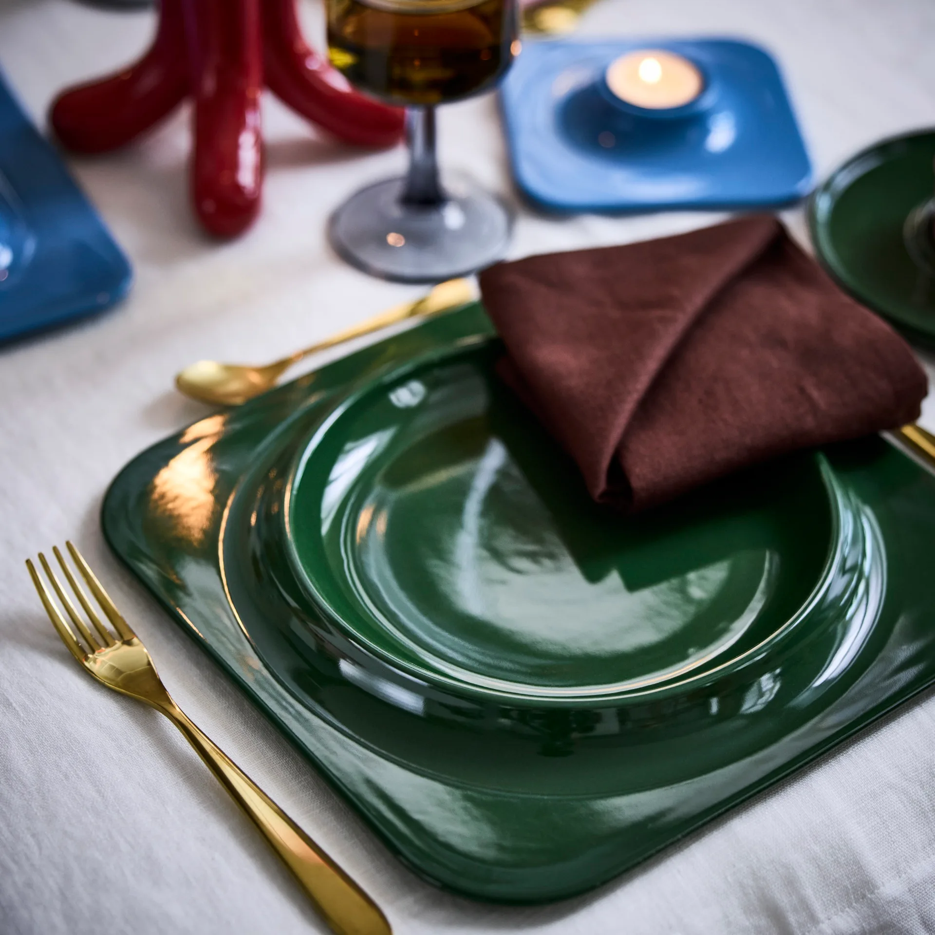 close up of vinterfint green plate with gold cutlery and red napkin on top