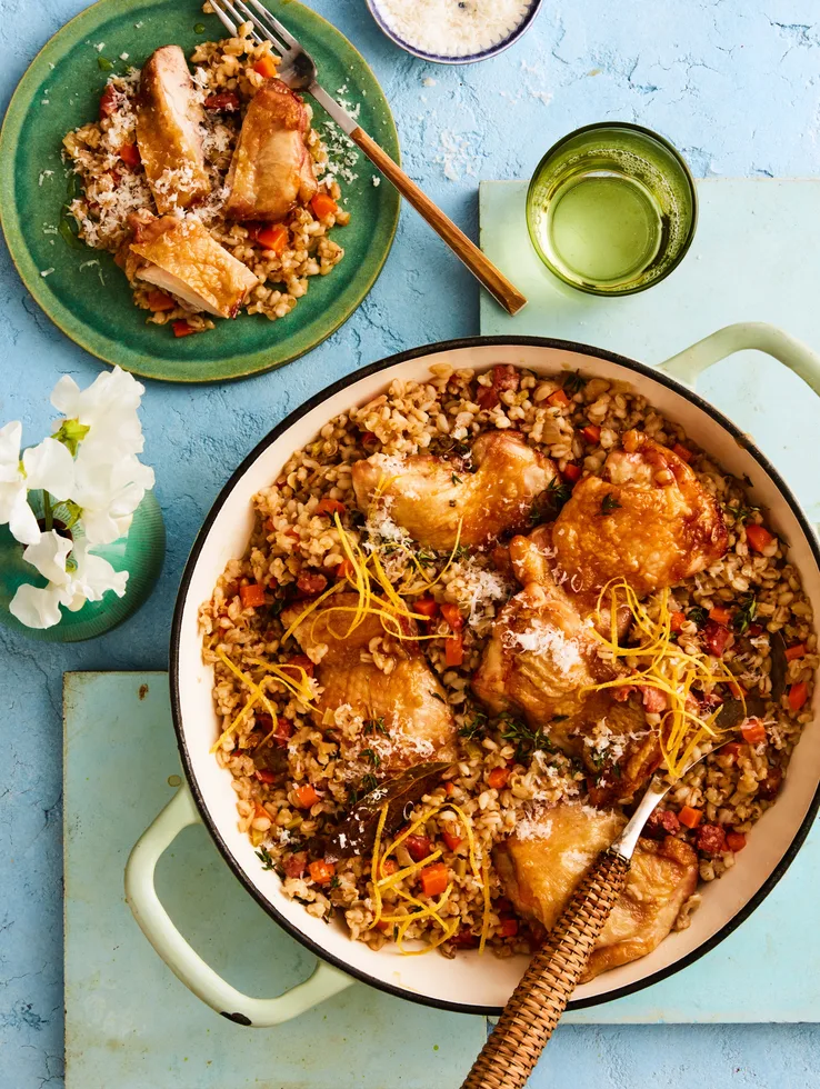 pearl barley risotto with chicken in large pot with handles and wooden spoon sticking out