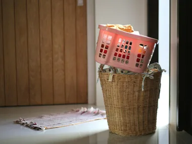 image of laundry hamper with plastic basket balacing on top filled with clothes