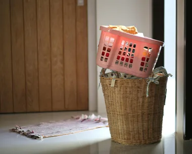 image of laundry hamper with plastic basket balacing on top filled with clothes