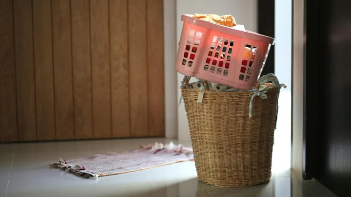 image of laundry hamper with plastic basket balacing on top filled with clothes