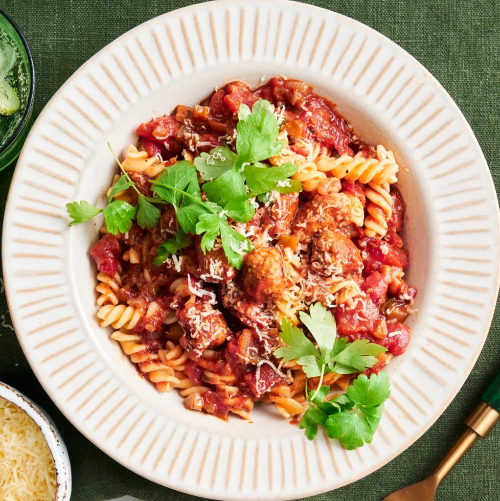 pork and fennel meatball pasta with parsley and parmesan on top in white bowl