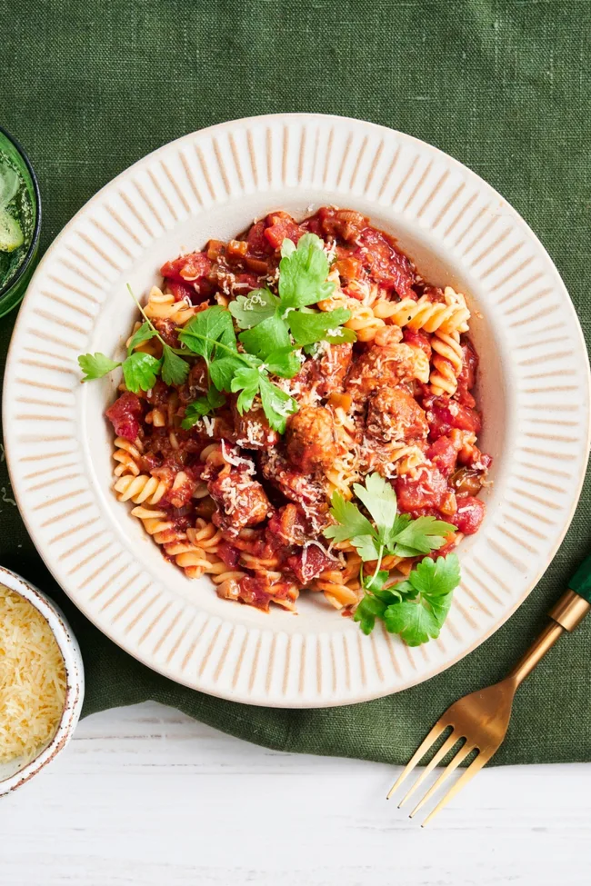 pork and fennel meatball pasta with parsley and parmesan on top in white bowl
