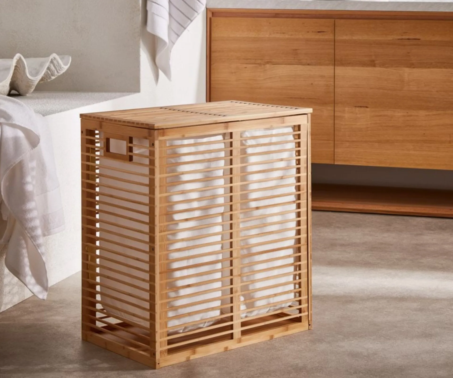 wooden bamboo laundry basket with lining in bathroom with wooden cabinet behind