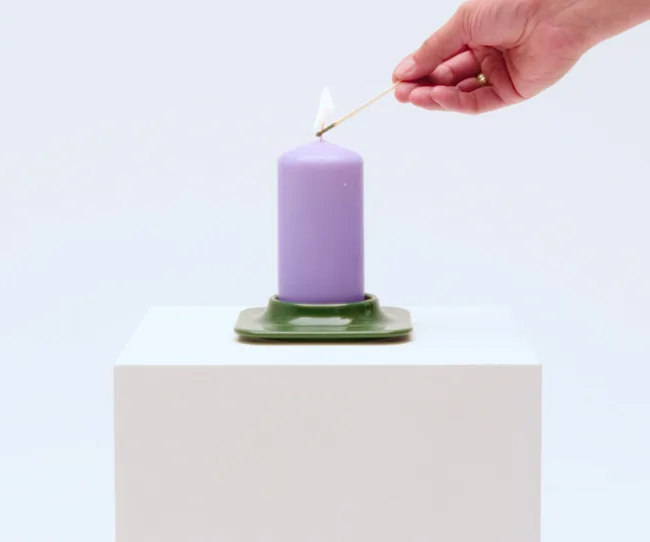 vinterfint candle holder in green with purple candle being lit by a hand