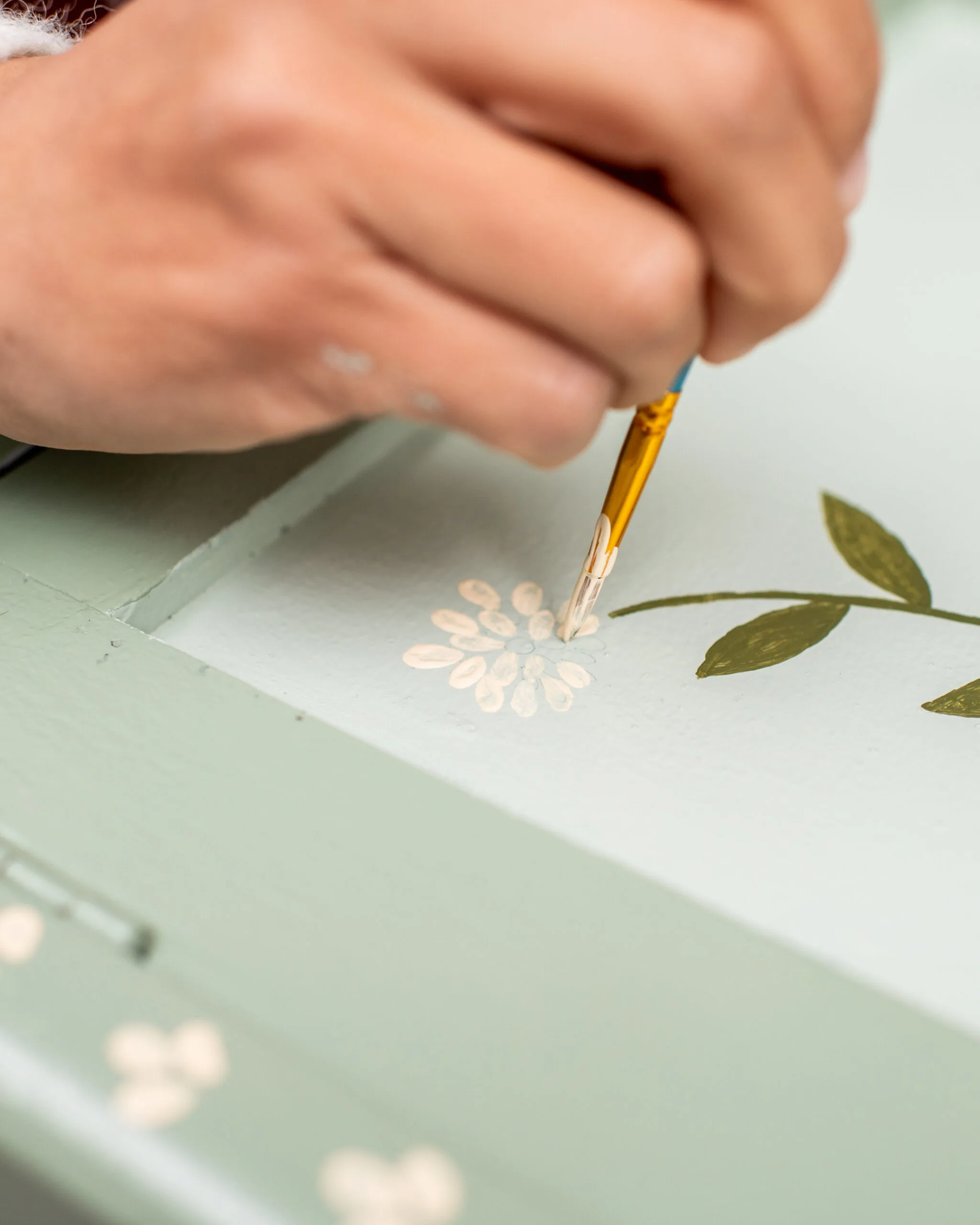 flor branca sendo pintada à mão em um armário verde