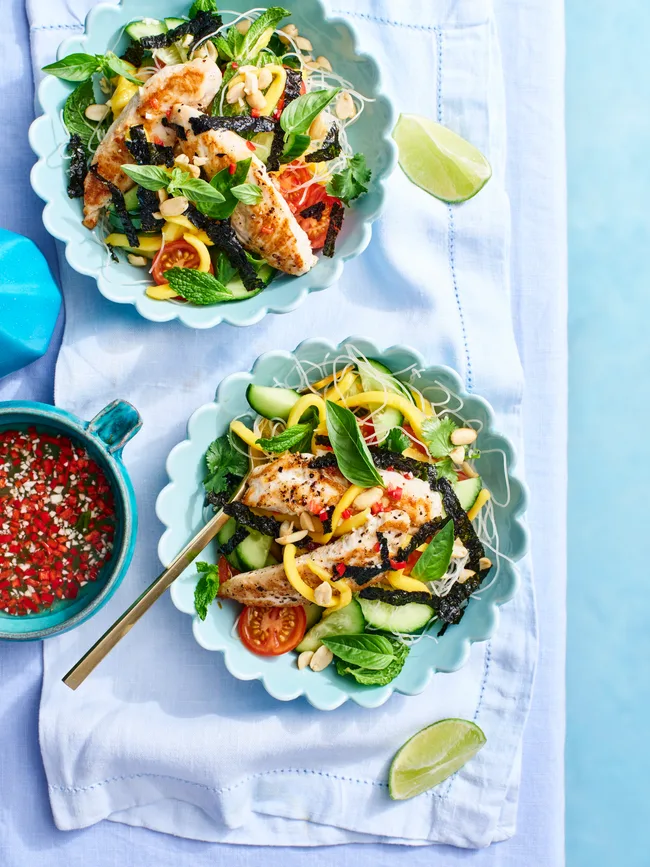 chicken vermicelli salad with chunks of mango and blue scalloped bowls