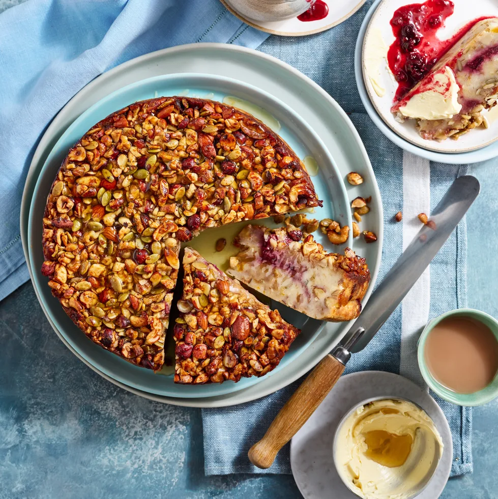 bread and butter cake recipe with cake covered in nuts and seeds with two slices cut to show cross section