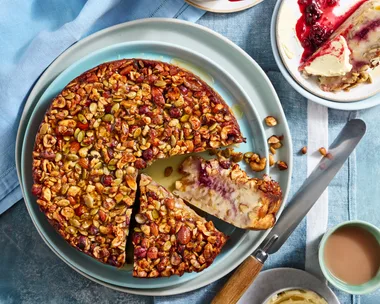 bread and butter cake recipe with cake covered in nuts and seeds with two slices cut to show cross section