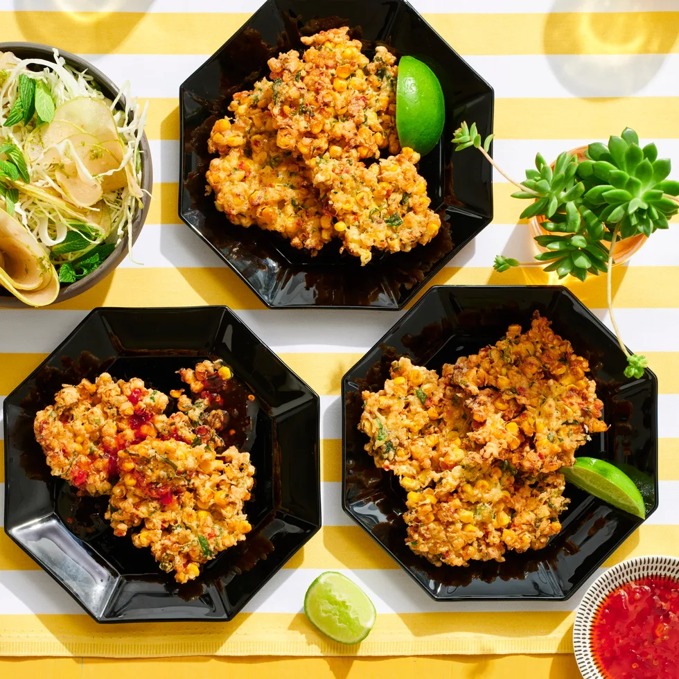 corn fritters in three hexagonal black plates with lime wedges on the side