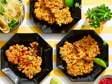 corn fritters in three hexagonal black plates with lime wedges on the side