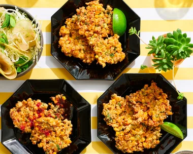 corn fritters in three hexagonal black plates with lime wedges on the side