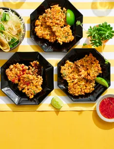 corn fritters in three hexagonal black plates with lime wedges on the side