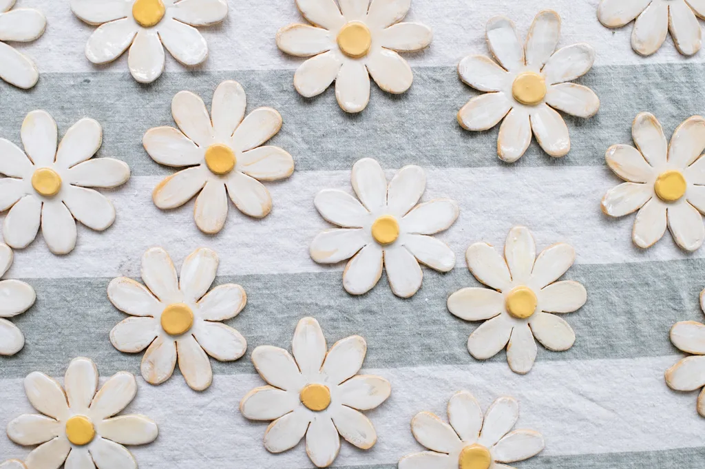 finished clay flowers with yellow centre sitting on stripy grey and white tablecloth