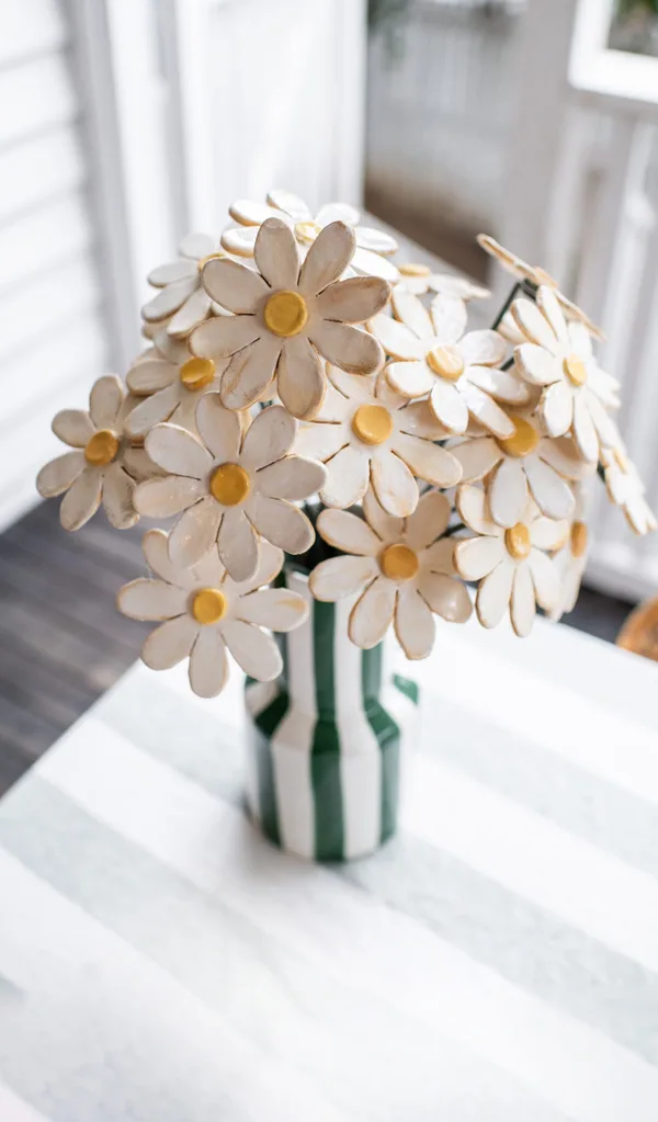 close up of clay flowers bouquet in green stripy vase