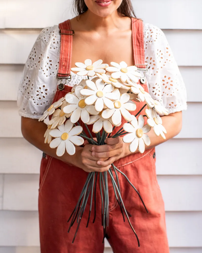 clay flower bouquet held in geneva's hands with her red overalls shown in the background