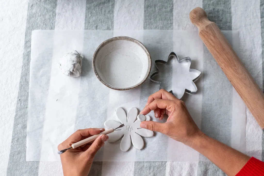 hands shaping clay flowers and putting in centre stamen circle