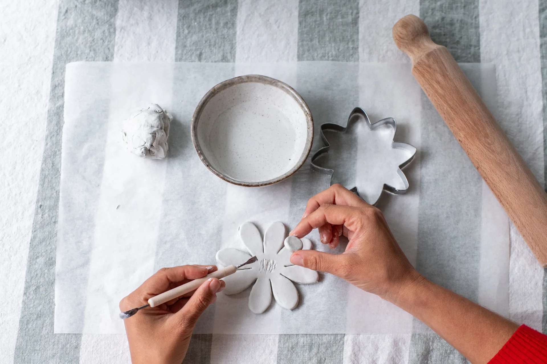 mãos moldando flores de argila e colocando no centro o círculo do estame