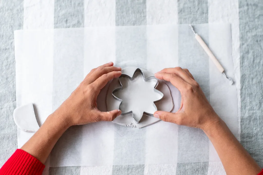 hands using cookie cutter to make flower shape in air dry clay