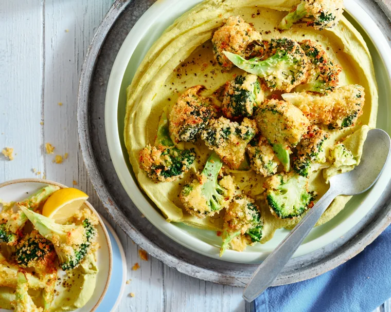 A homemade hummus with crispy broccoli on top.