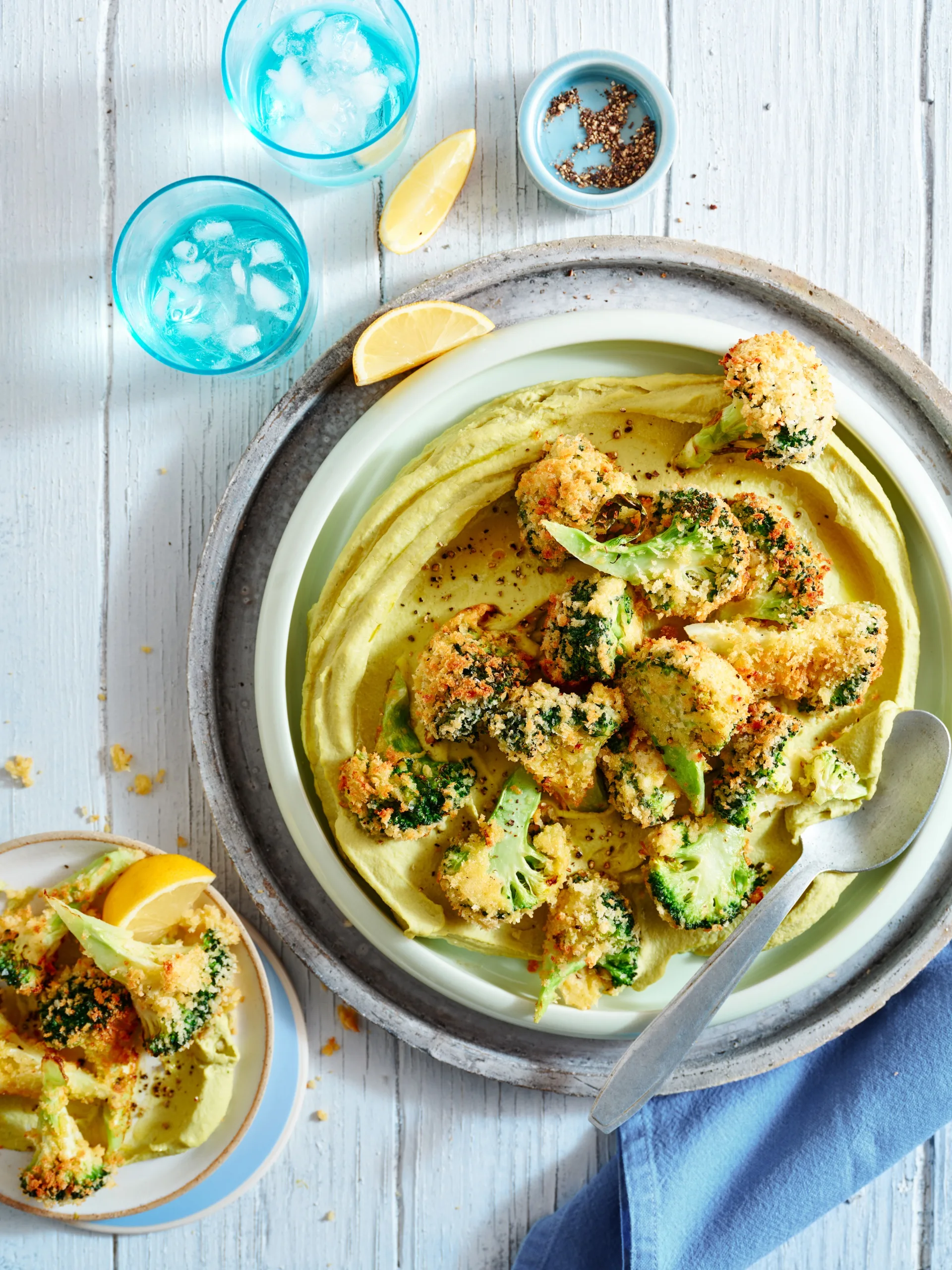 A homemade hummus served with crispy broccoli on top.