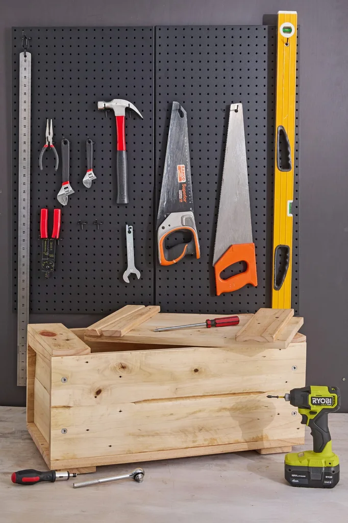 wooden toolbox diy with tools on grate behind it and drills on top
