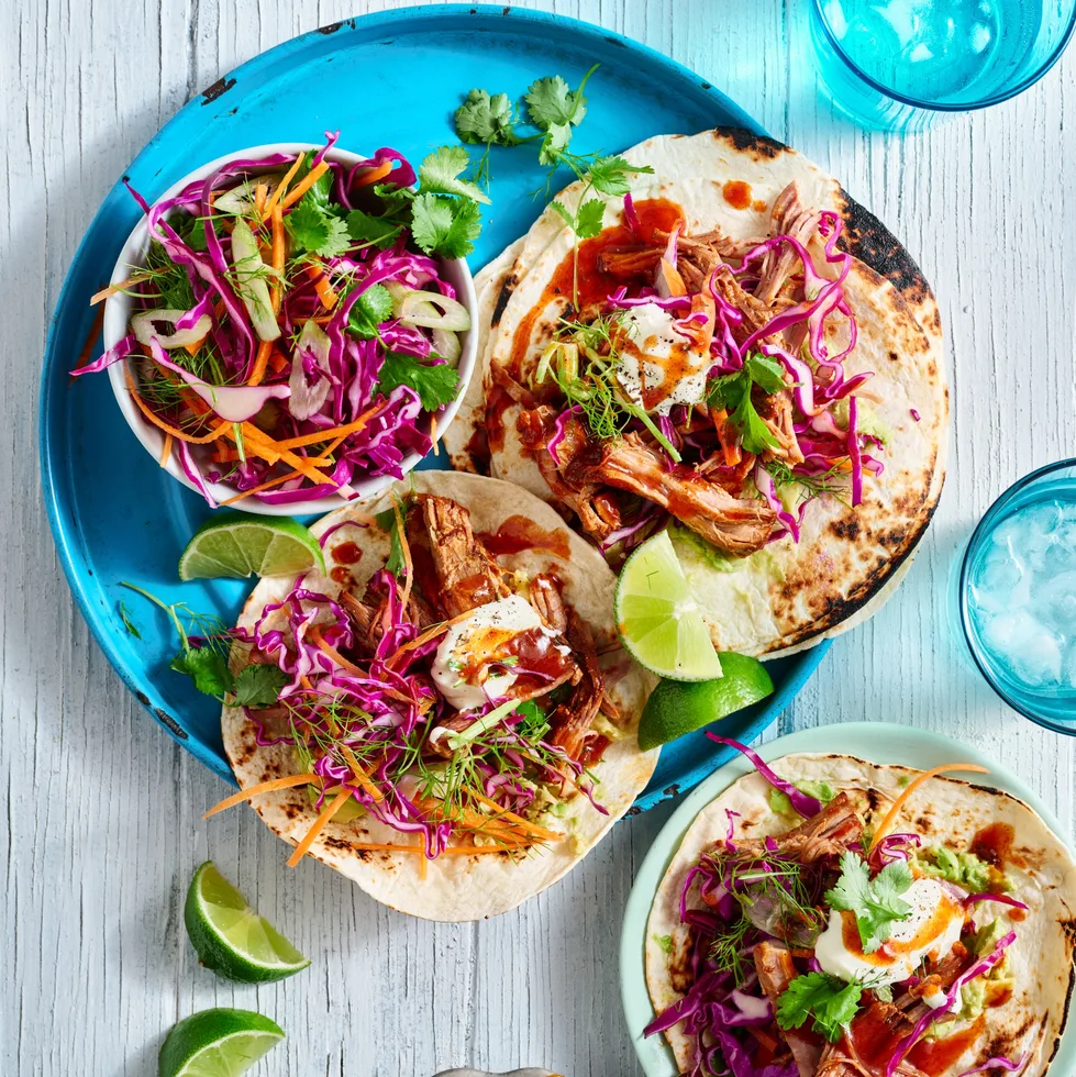 pulled pork tacos open on plate with cabbage slaw on top and in bowl on the side