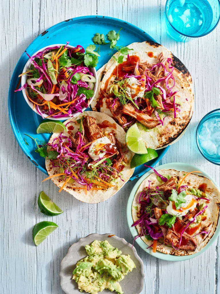 pulled pork tacos open on plate with cabbage slaw on top and in bowl on the side