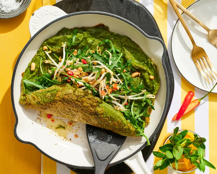 spiced green eggs omelette in pan with spatula pushing it up