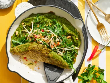 spiced green eggs omelette in pan with spatula pushing it up