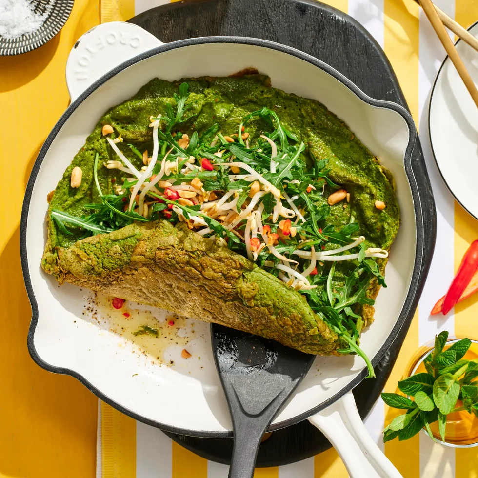 spiced green eggs omelette in pan with spatula pushing it up