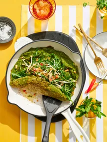 spiced green eggs omelette in pan with spatula pushing it up