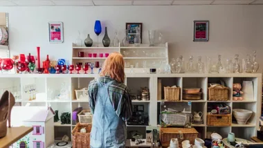 young woman with pink hair looking in an op shop