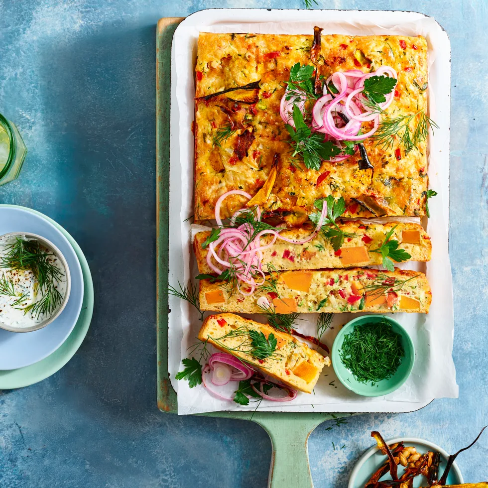 zucchini and pumpkin slice cut up on wooden board with dill yoghurt on the side and glasses of lemonade
