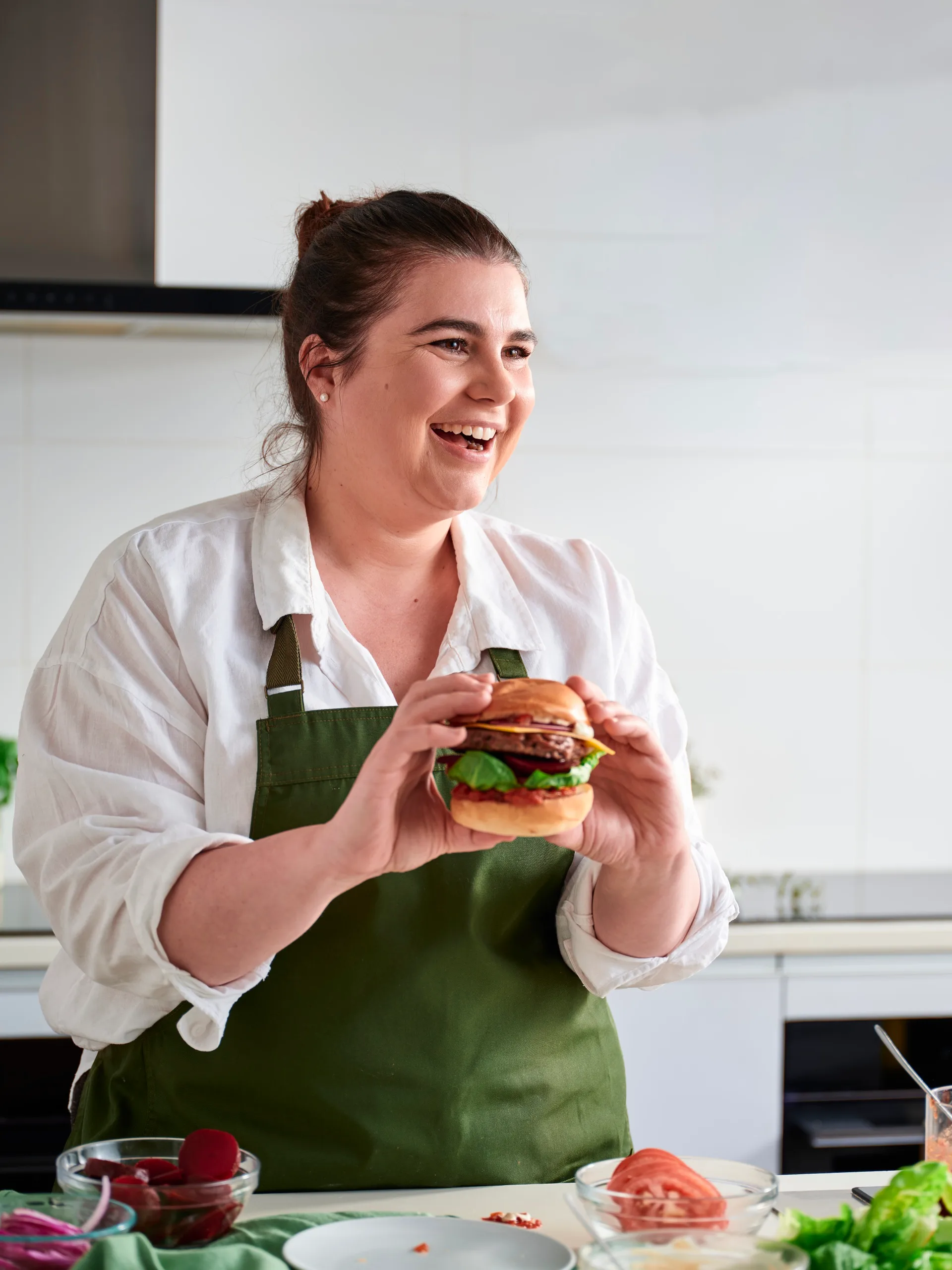 BHG senior food editor Sarah Murphy holding a big Aussie burger with beef, beetroot, cheese and French onion sauce