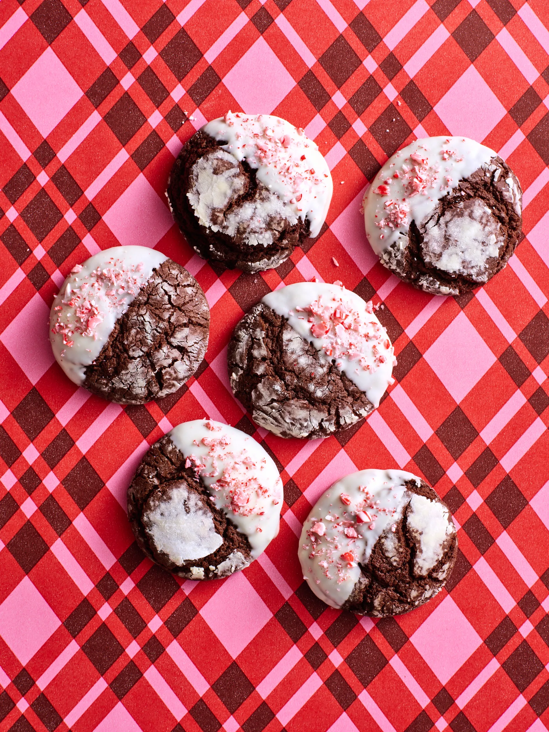 chocolate crinkle cookies with crushed candy cane topping on stripy pink tartan background