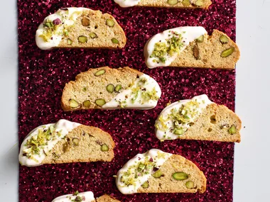 christmas biscotti laid out on red sparkly background with drizlle of white chocolate