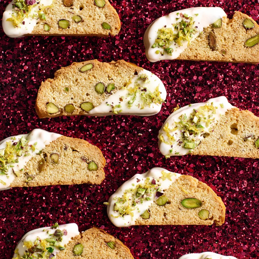 christmas biscotti laid out on red sparkly background with drizlle of white chocolate