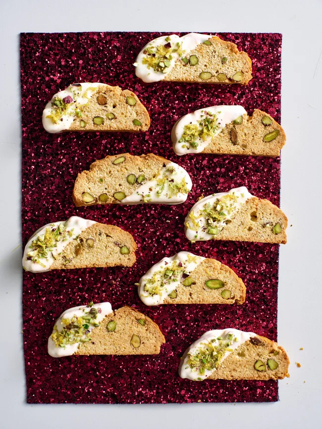 christmas biscotti laid out on red sparkly background with drizlle of white chocolate