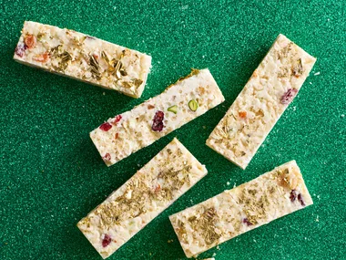 White christmas cut into small rectangular pieces with gold leaf on top and green sparkly background