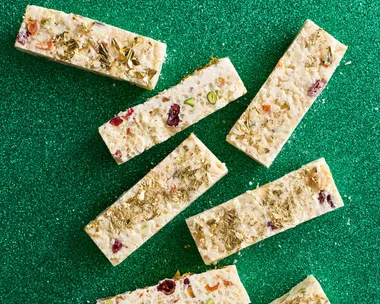 White christmas cut into small rectangular pieces with gold leaf on top and green sparkly background