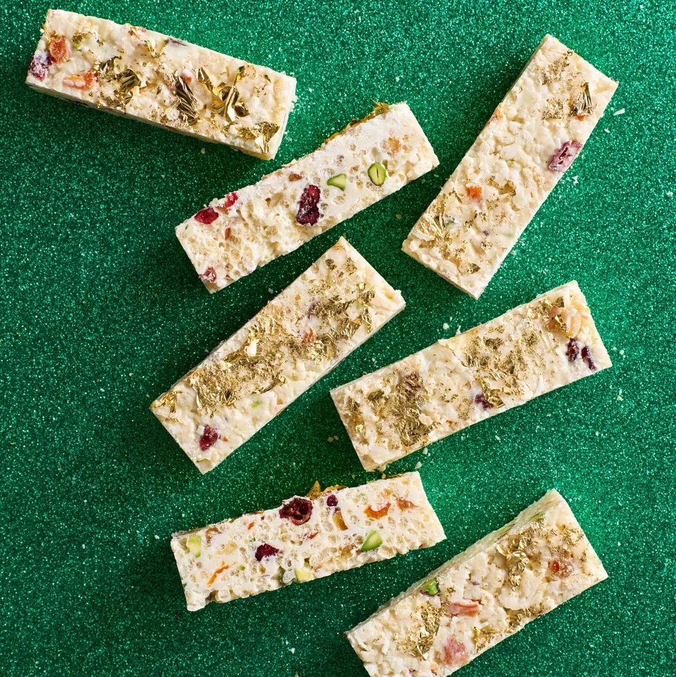 White christmas cut into small rectangular pieces with gold leaf on top and green sparkly background