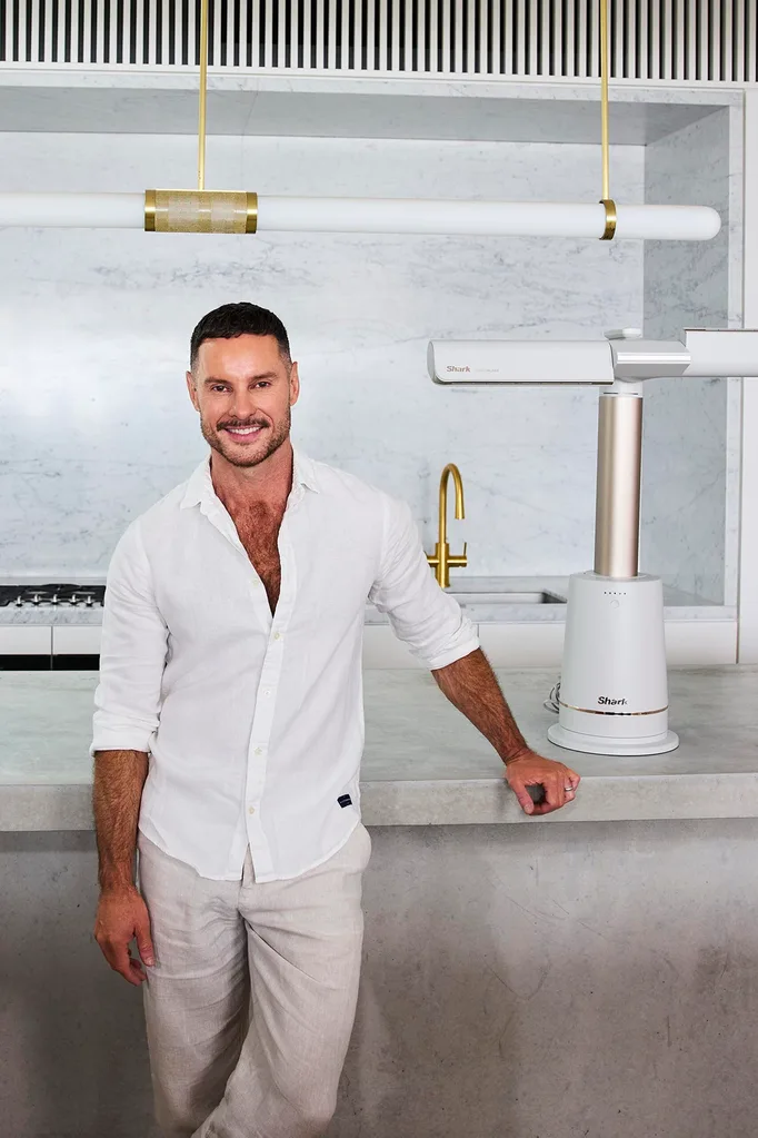 Interior designer Darren Palmer standing in a white marble kitchen with a Shark TurboBlade fan next to him