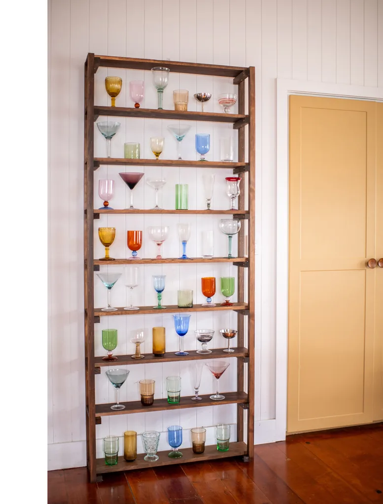 glassware display shelf with coloured glasses on dark brown wooden shelving unit