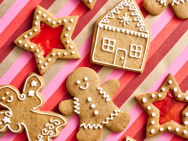 gingerbread recipe with gingerbread men stars with lolly centre and gingerbread 2D houses on stripy pink and red tablecloth