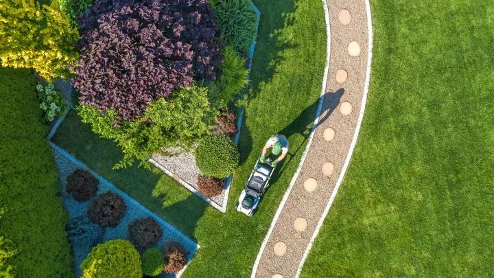 Gardener landscaping garden with mower